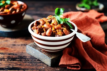Beef stew with beans, tomatoes and vegetables on a dark wooden background