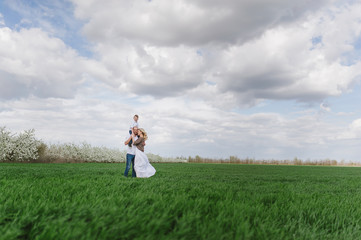  Family on a walk in a field with green grass and blue sky, early spring, good weather, happy family, white clothes