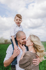  Family on a walk in a field with green grass and blue sky, early spring, good weather, happy family, white clothes