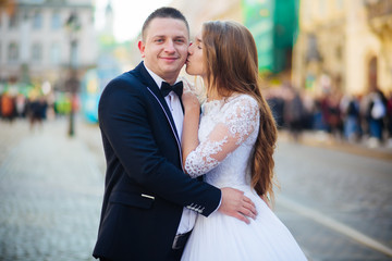 Fototapeta premium Bride and bridegroom walking across cobbled street