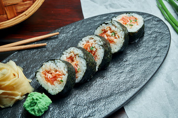 Classic japanese sushi rolls with salmon. California roll on a black plate with chopsticks. Japanese cuisine. Healthy seafood