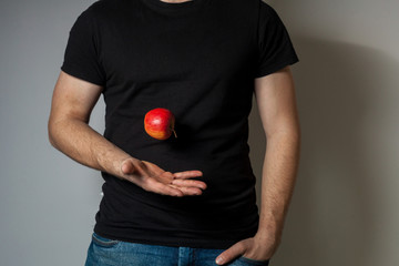 Red apple flying from one hand to another man in black football against gray wall background
