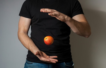 Red apple flying from one hand to another man in black football against gray wall background