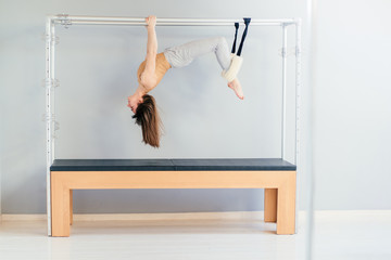 Pretty Pilates Instructor Hanging Upside Down from Trapeze Table