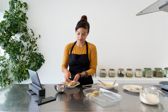 Brunette woman streaming a cooking class with some homeade recipes from her kitchen