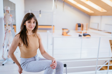 Back view of woman doing reformer pilates stretching exercise.