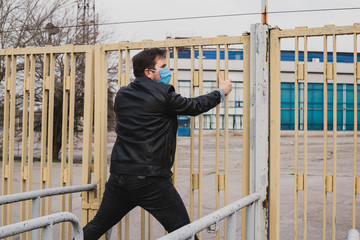 man in mask climb over the fence, refugee concept, coronavirus quarantine.