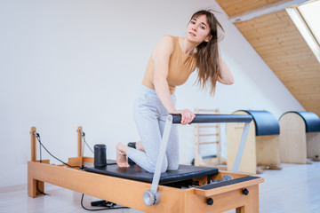Healthy Smiling Brunette Woman Wearing Leotard and Practicing Pilates in Exercise Studio