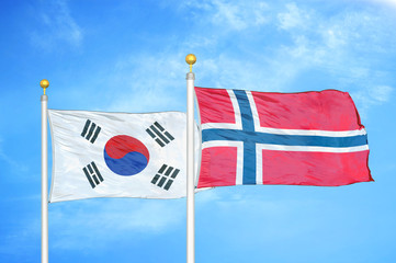 South Korea and Norway two flags on flagpoles and blue cloudy sky