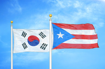 South Korea and Puerto Rico two flags on flagpoles and blue cloudy sky