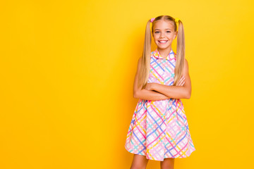Photo of pretty funny little lady arms folded good mood toothy smiling pretty long tails hairdo enjoy weekend wear checkered plaid summer dress isolated yellow vivid color background