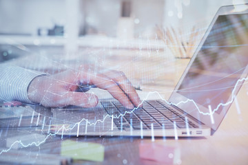 Double exposure of stock market graph with man working on laptop on background. Concept of...