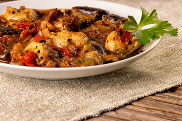 Side view of a plate with stew on a napkin on a wooden surface