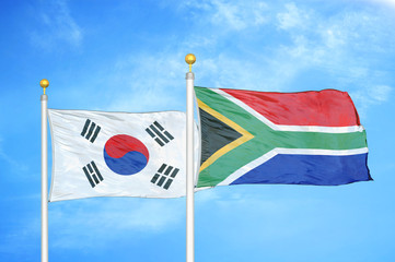 Naklejka premium South Korea and South Africa two flags on flagpoles and blue cloudy sky