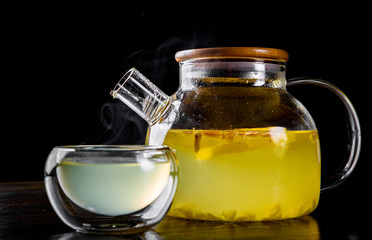 tea pot and Cup of ginger tea with honey and lemon on black background