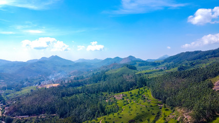 Fototapeta na wymiar Tea plantations in Munnar, Kerala, India. Beautiful views of green hills with blue sky.
