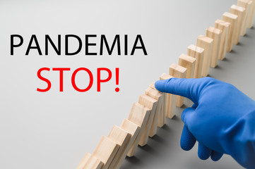 Stop COVID-19. A hand in a blue medical glove stops the domino effect. Preventive measures to combat the global spread of the coronovirus pandemic. Horizontal orientation.