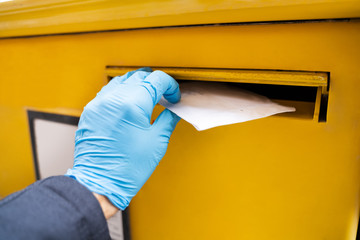 Man Inserting Letter In Mailbox Wearing Gloves