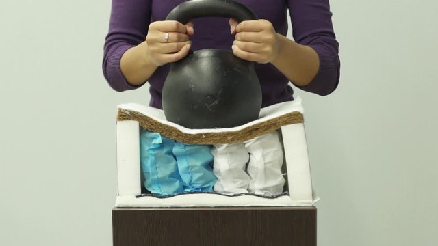 Woman puts a heavy weight on orthopedic mattress with an independent spring unit