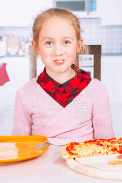 Funny imahe of little cute child girl eating a piece of pizza. Happy childhood, food, rest and joy concept.