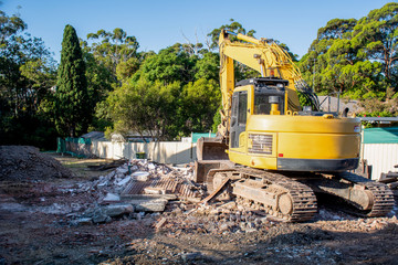 Excavator working on demolition of the resedential building. Debris on the construction site