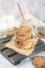 Oatmeal raisin on paper and a wooden stand with milk in the background