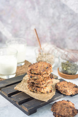 Oatmeal raisin on paper and a wooden stand with milk in the background vertical arrangement