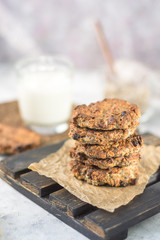 Oatmeal raisin on paper and a wooden stand with milk in the background