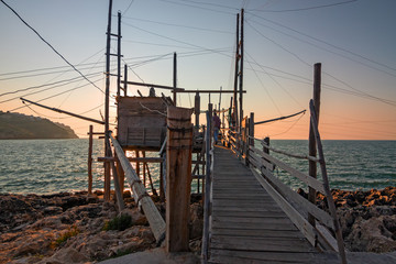 Fototapeta premium Trabucco, ancient wooden structure of the fishermen of the lower Adriatic Sea in the Gargano in Italy, in the sunset light.