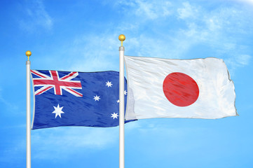 Australia and Japan two flags on flagpoles and blue cloudy sky