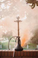 Hookah outdoors on a background of colored smoke