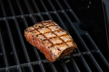 beef roast beef steak seasoned with coarse pepper and sea salt with flames on the grill with beautiful stripes