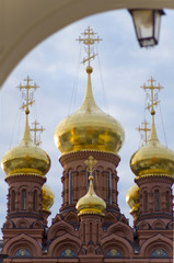 Fototapeta na wymiar The Chernigovsky skete in Sergiev Posad, Russia, golden domes on the huge belfry above the gate