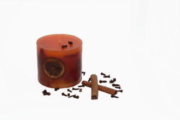 Orange candle with cinnamon sticks and cloves isolated on white
