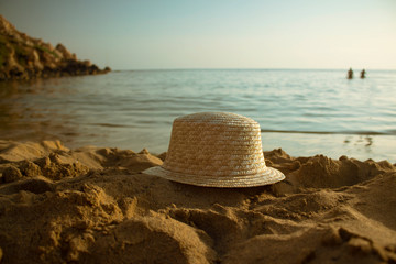 Straw hat laying on a beach at seashore in susnset time