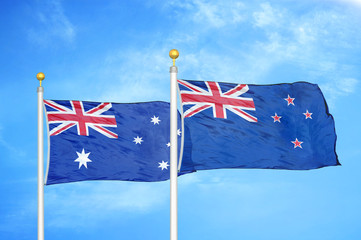 Australia and New Zealand two flags on flagpoles and blue cloudy sky