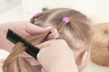 Fototapeta premium mother hands combing a comb little three-year-old girl
