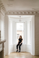 Fototapeta premium Girl in black clothes near the bay window