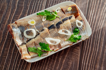 sliced salted herring on plate onion rings  lemon