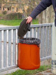 Responsible dog owner puts poo, excrement in bin, outdoors in park. Unidentifiable person, UK.