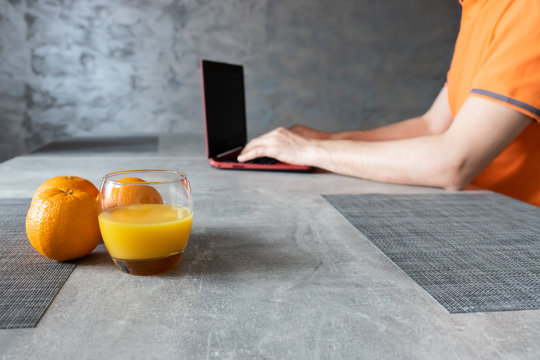Zdrowy tryb życia w pracy,świeże pomarańcze i szkło ze sokiem. Męzczyzna pracuje na laptopie.