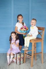 Obraz premium Happy school children in a uniforn with big gingerbread pencils and bouquet of autumn flowers