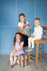 Happy school children in a uniforn with big gingerbread pencils and bouquet of autumn flowers