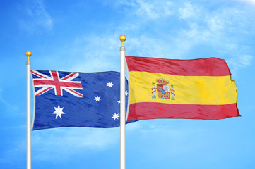 Australia and Spain two flags on flagpoles and blue cloudy sky