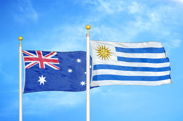 Australia and Uruguay two flags on flagpoles and blue cloudy sky