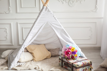 Wigwam at home, suitcase and bouquet of flowers