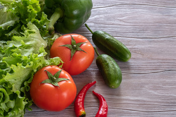 Fresh, juicy green and red vegetables on a wooden table