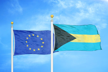European Union and Bahamas two flags on flagpoles and blue cloudy sky