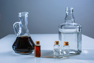 A large decanter and a test tube with a dark liquid stand next to the decanter and test tubes with a light liquid