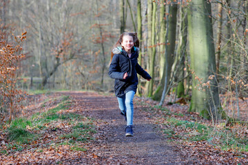 A girl is running on a path in the woods